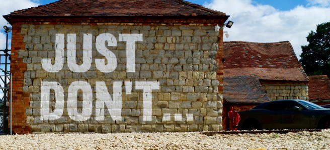 A brick building with the words 'JUST DON'T...' painted in white, symbolizing the importance of saying no and setting boundaries for personal growth and a minimalist mindset.