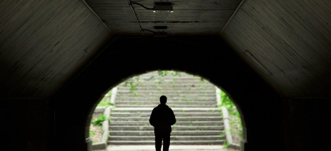 Silhouette of a person walking out of a dark tunnel into a bright, light-filled exit, symbolizing the transition from extreme focus to a balanced life.