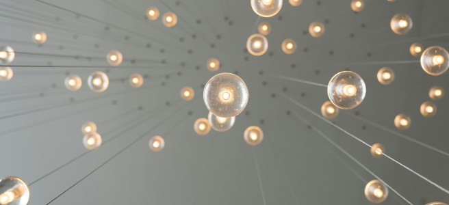 Glowing light bulbs suspended from the ceiling, representing creative ideas and a scattered thought process for creative growth.