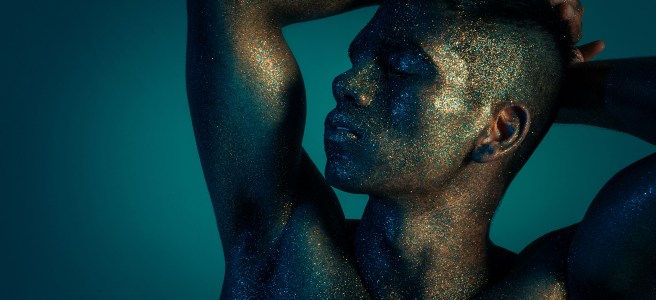 A person covered in glitter, striking a relaxed pose with eyes closed, representing creativity, openness, and innovative thinking.