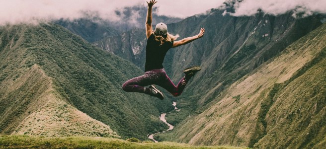 A person jumping in the air with mountains in the background, symbolizing embracing a creative mindset and personal growth.