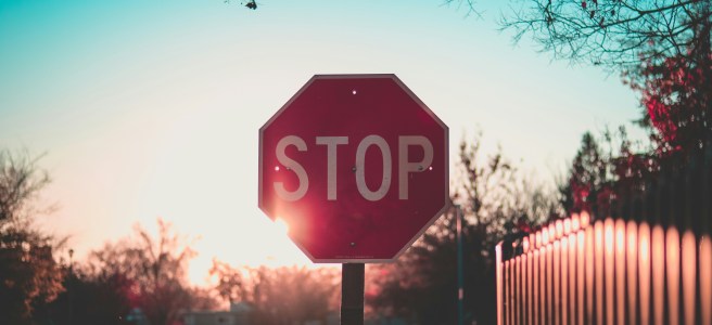 Stop sign illuminated by sunset, symbolizing the decision to pause, reflect, and consider quitting a project or path that no longer serves personal growth.